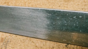 The left side of this piece of aluminum stock is prepared for welding. The oxide layer remains visible on the right. (WelditU)