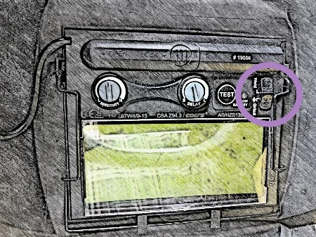 Illustration showing location of a grind mode switch on the inside of a welding helmet.